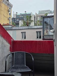 a chair sitting on a balcony with a red wall at Urban House in Batumi