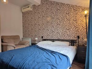 a bedroom with a bed and a chair and a wall at Urban House in Batumi