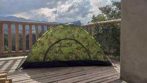 a green tent sitting on a wooden deck at Camping luz do sol in Aiuruoca