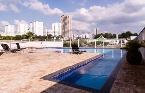a swimming pool with chairs and a table and buildings at Flat Red Encanto in Sorocaba