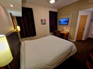 a hotel room with a bed and a television at Charter Hotel Bournemouth in Bournemouth +9 photos