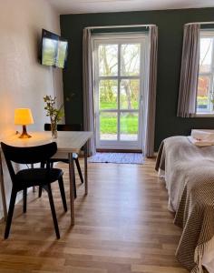 a bedroom with a table and a bed and a window at Nygaard Livsnyderi in Læsø