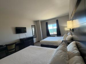 a hotel room with two beds and a flat screen tv at Black Gold Suites Stanley in Stanley