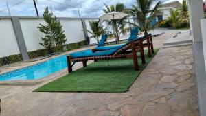a couple of chairs and an umbrella next to a pool at Palm Residence Vacation Villa in Nungwi