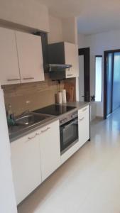a kitchen with white cabinets and a sink and a stove at Green Garden in Gajac