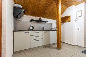 a kitchen with white cabinets and a wooden ceiling at Morena in Klaipėda