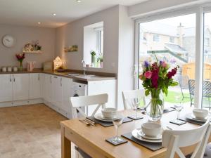 a kitchen with a table with a vase of flowers on it at Llifon in Llanwnda