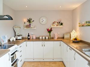 a kitchen with white cabinets and a clock on the wall at Llifon in Llanwnda +11 photos