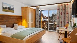 a bedroom with a bed and a large window at Hotel Bergsonne Allgäu in Sonthofen