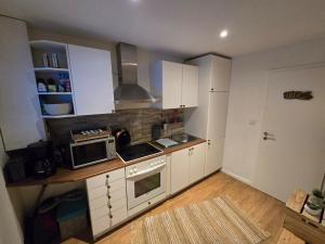a small kitchen with white cabinets and a microwave at Mimos Ferienhaus in Meißendorf