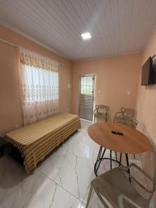 a bedroom with a bed and a table and chairs at Pousada Bela Rosa in Santa Cruz Cabrália