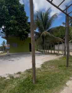 a yellow building with palm trees in front of it at Pousada Bela Rosa in Santa Cruz Cabrália