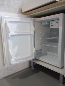 an empty refrigerator with its door open in a kitchen at Basaltic House Pedreira in Lomba da Pedreira