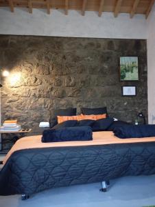 a bedroom with a large bed with a stone wall at Basaltic House Pedreira in Lomba da Pedreira