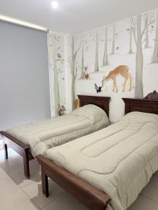 a bedroom with two beds and a mural of trees at Cabildo Apart Familiar in Santiago del Estero