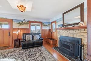 a living room with a fireplace and a black leather chair at Coastal Craftsman in Pacific City