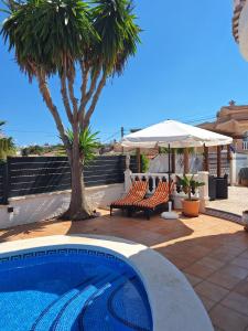 a swimming pool with two chairs and an umbrella at casa des loups in Ciudad Quesada