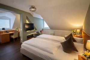 a bedroom with a bed and a desk and a television at Hotel Bayrischer Hof in Heidelberg