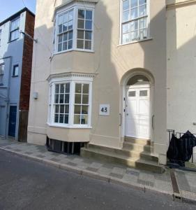 a white house with a white door on a street at Weymouths Coastal Nook in Weymouth