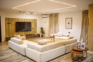 a living room with two white couches and a flat screen tv at Avenue 28th Apartment in Benin City