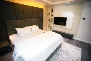 a bedroom with a large white bed and a flat screen tv at Avenue 28th Apartment in Benin City +14 photos