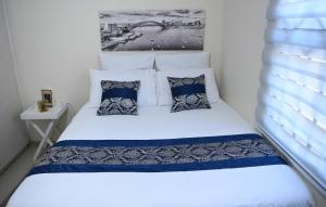 a bedroom with a white bed with blue sheets and pillows at Twinhome Inn in Gaborone