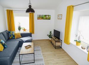 a living room with a blue couch and yellow curtains at Ferienwohnung Schusternagerl in Simbach