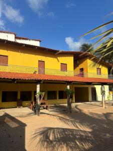 a yellow building with a picnic table in front of it at Pousada Raios do Sol in Amontada