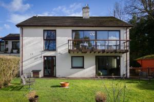 a white house with a balcony and a yard at Meadfoot Guesthouse Room only accommodation for Adults in Windermere