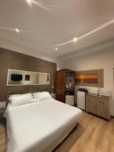 a bedroom with a large white bed and a kitchen at Il Viale in Imola