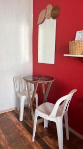 a table and chairs in a room with a red wall at Pousada Suítes Sete Mares in Guarujá