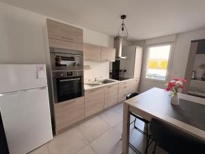 a kitchen with a white refrigerator and a table at Appart Cosy 50 m2 avec balcon à Amnéville, Metz et Luxembourg in Amnéville