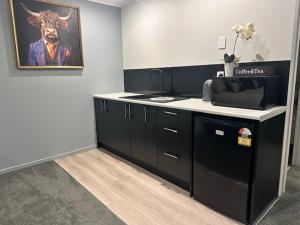 a kitchen with black cabinets and a painting of a cow at Thornton Hideaway Private Standalone Retreat, Walk to Cambridge Town Centre in Cambridge