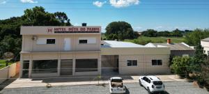 a building with two cars parked in a parking lot at Hotel e Restaurante Rota do Pampa in Estância Teixeira