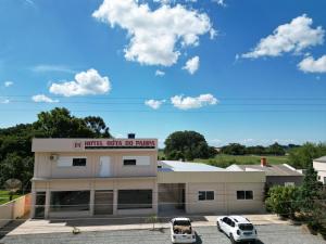 a building with two cars parked in a parking lot at Hotel e Restaurante Rota do Pampa in Estância Teixeira