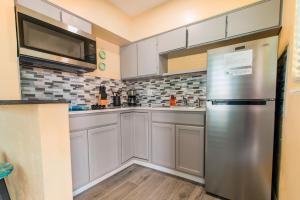 a kitchen with white cabinets and a stainless steel refrigerator at Gorgeous Beach Condo in St. Petersburg