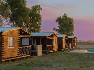 a row of wooden lodges in a field at CABAÑAS BRUTUS RANCHs in Azul