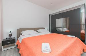 a bedroom with a large orange bed with a mirror at Apartment Adriatic panorama view in Omiš