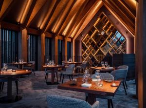 a restaurant with wooden tables and chairs and wooden ceilings at YONA ex Le Parc Hôtel in Obernai