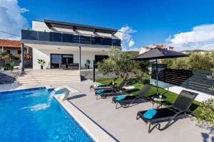 a pool with chairs and an umbrella next to a house at Villa dal' Mares in Vinišće