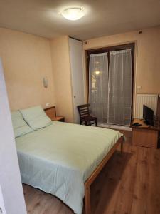a bedroom with a bed and a desk and a window at La Bona Taula By A&J in Rochefort-Montagne