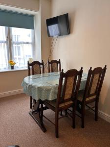 a dining room table with four chairs and a television at Apartment 2 at 2 Bell Street in Talgarth