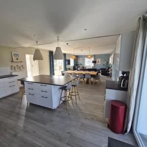 a kitchen and living room with a table and chairs at "La Villa du Cap" avec piscine intérieur, billard et à 5 minutes de la plage et des commerces! in Fouesnant