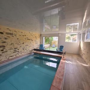 a swimming pool with blue chairs in a house at "La Villa du Cap" avec piscine intérieur, billard et à 5 minutes de la plage et des commerces! in Fouesnant