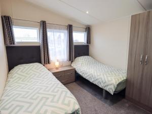 a bedroom with two beds and a dresser and a window at Lily's Lodge in Morecambe