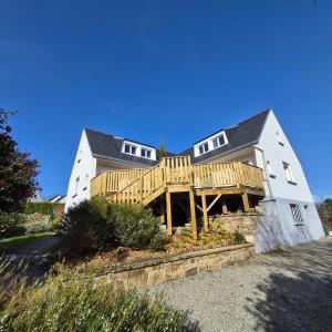 a large white house with a wooden deck at "La Villa du Cap" avec piscine intérieur, billard et à 5 minutes de la plage et des commerces! in Fouesnant