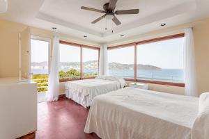 two beds in a bedroom with a view of the ocean at Private villa, 6 bedrooms, 2 pools with views in Acapulco
