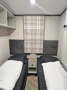 two beds in a small room with a window at Het mooiste plekje van het park in Kropswolde