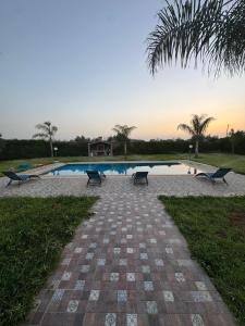 a swimming pool with benches in a park at villa lina in Aït Mazou +5 photos