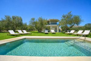 a swimming pool with chairs and a house at Luxury Villa Marian with Private Pool and Jacuzzi near the Beach of Georgioupoli in Georgioupolis